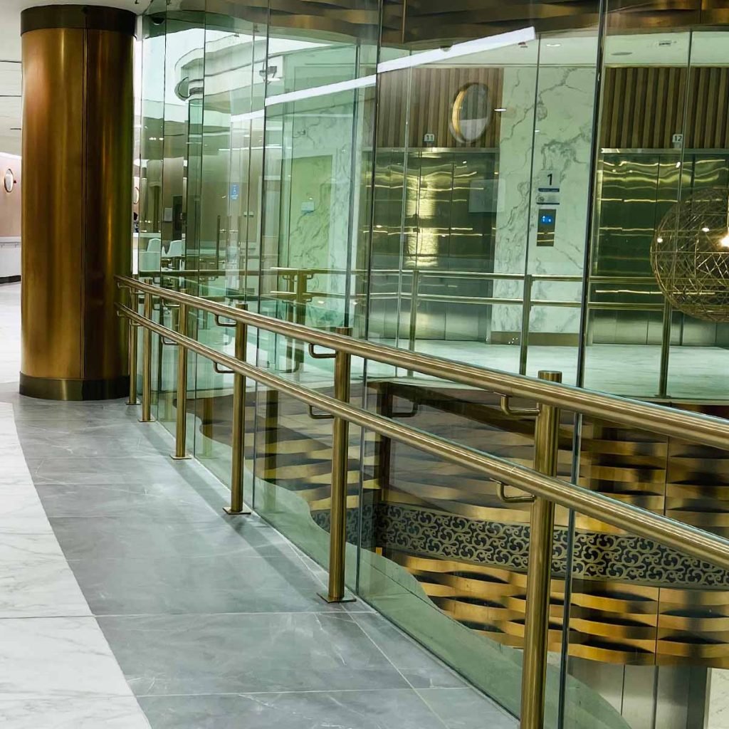 Architectural stainless steel balustrade with glass panels with gold metal handrails in a modern interior