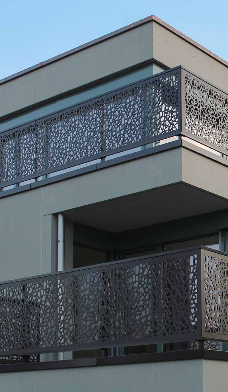 Custom architectural metal railing and balustrade system with laser-cut pattern designs for a contemporary building