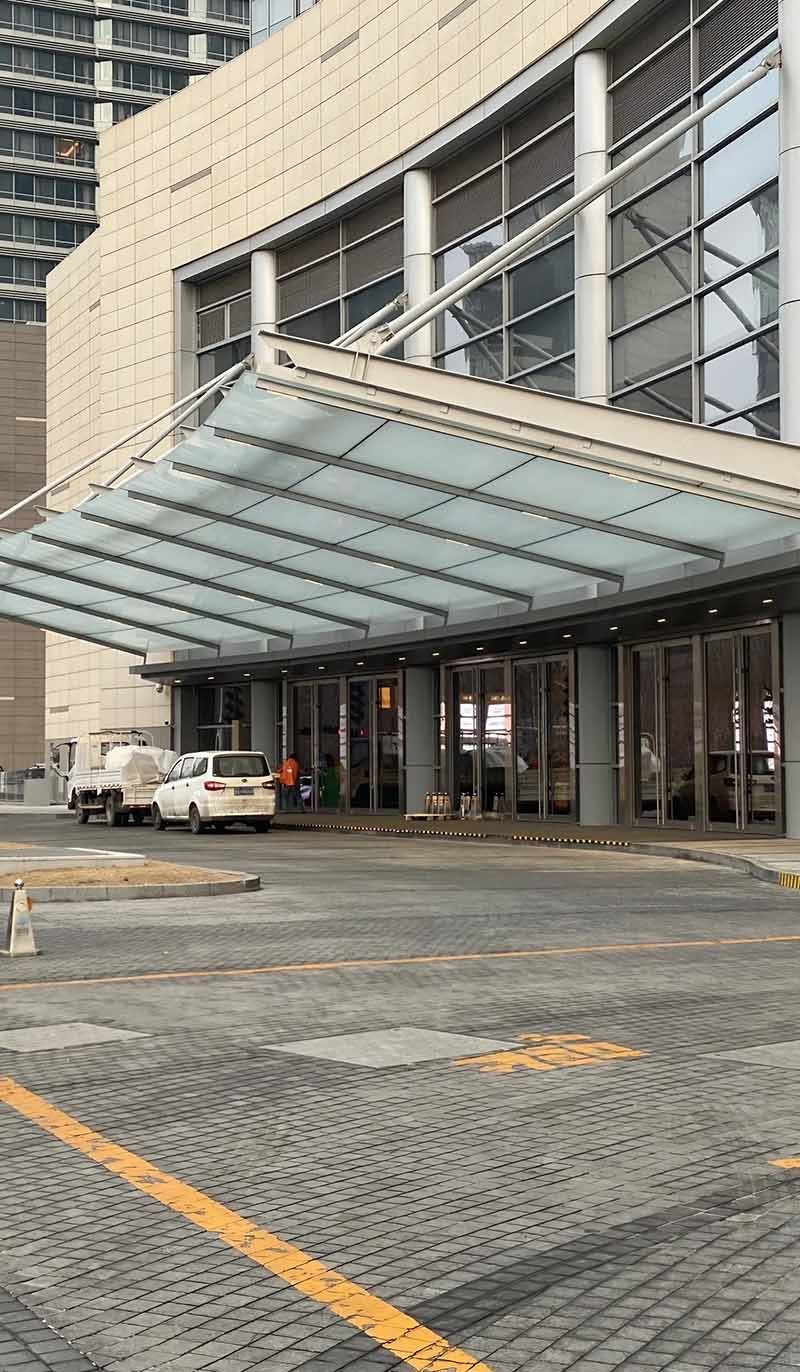 Custom-made stainless steel canopy with glass panels for a modern building entrance