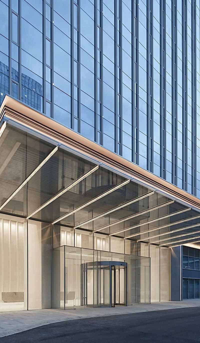 Custom glass canopy extending over a contemporary building entrance