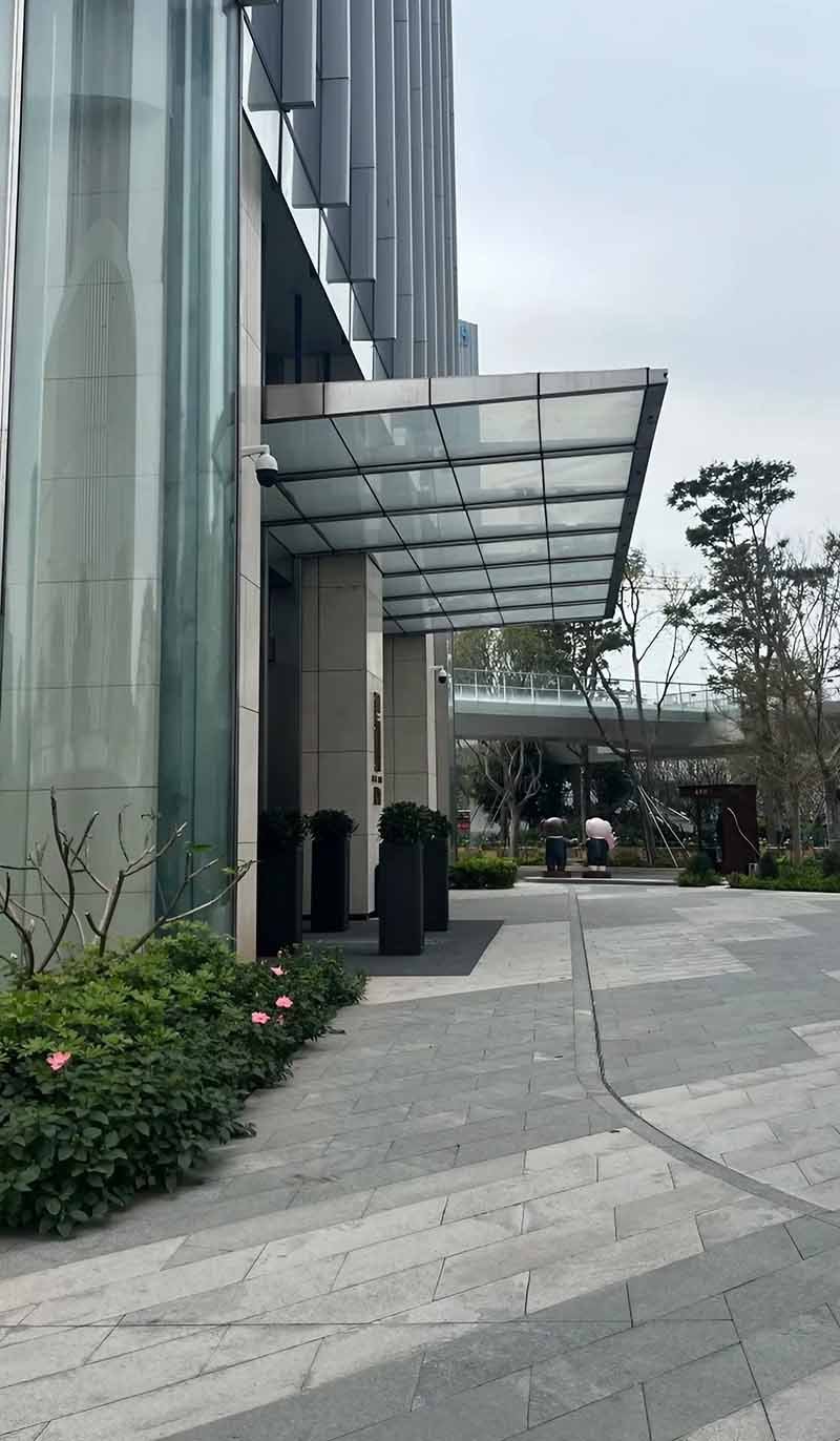 Stainless steel canopy extending over an entrance with clear glass roofing