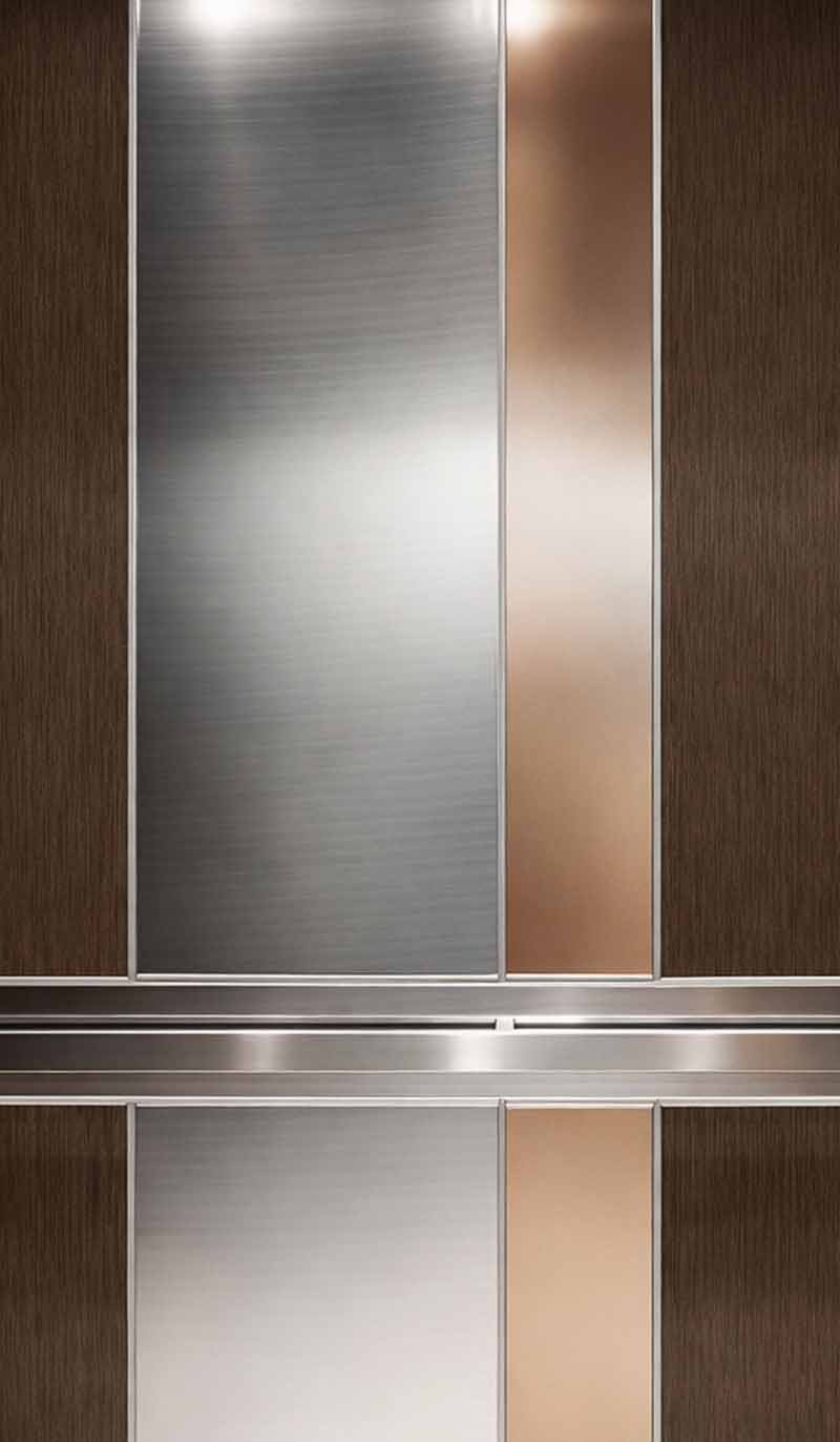 Custom stainless steel elevator interior wall panels with brushed steel, bronze, and wood-tone vertical sections