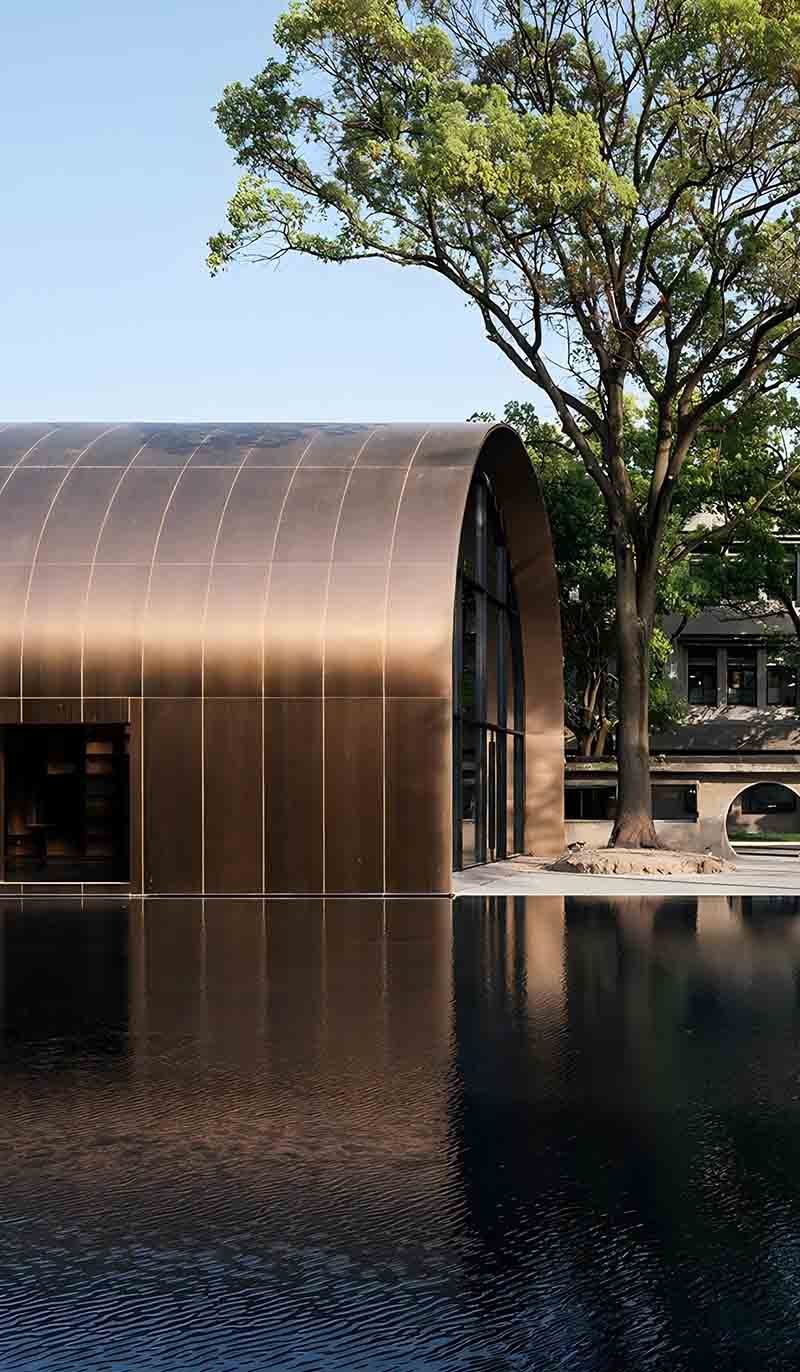 Copper facade cladding panels covering a contemporary building exterior with varied panel depths and glazing