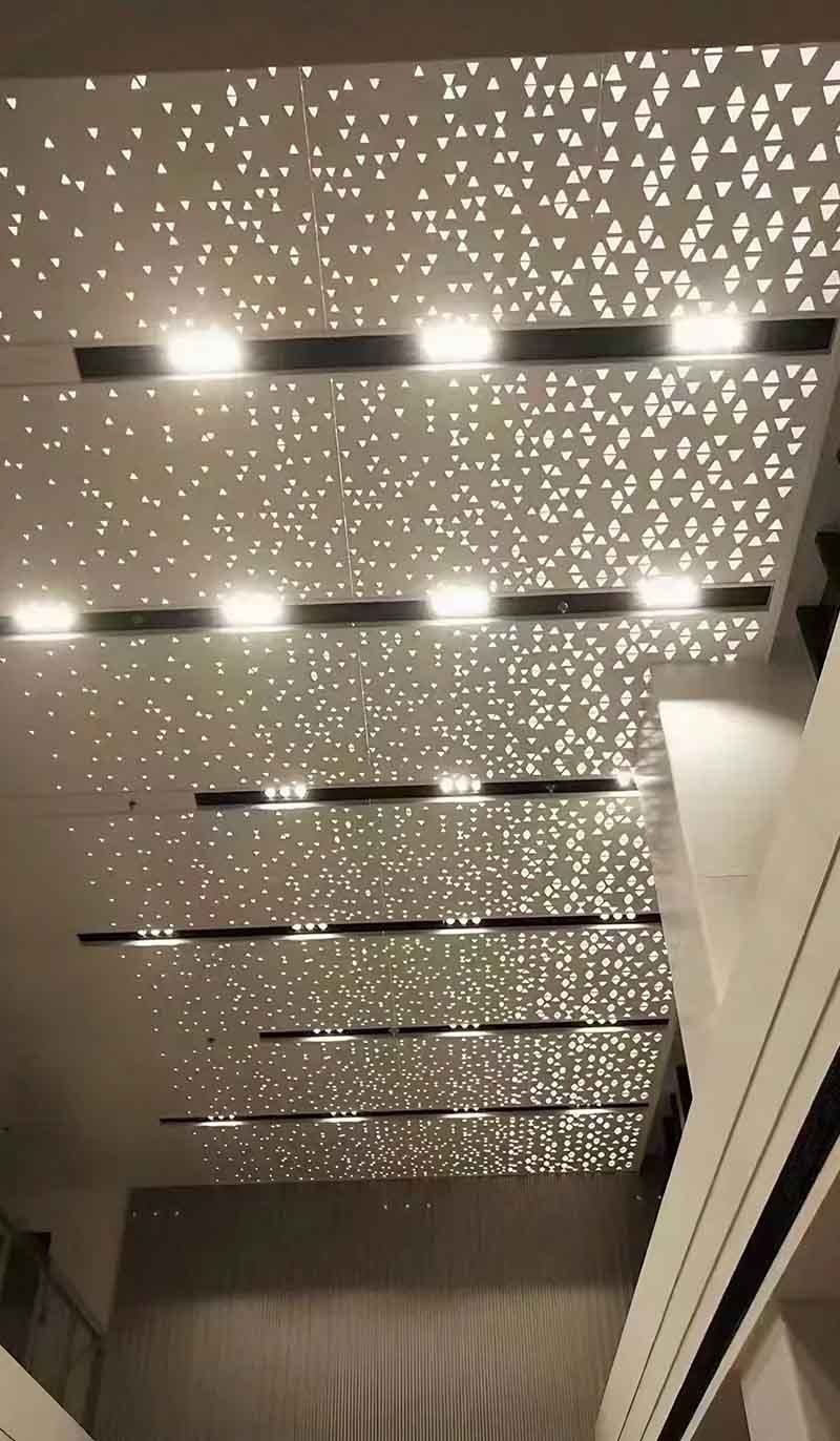 Architectural laser-cut metal ceiling with precision aluminium panels and decorative geometric perforation patterns in modern interior space