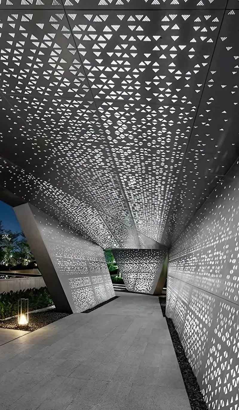 Modern laser-cut metal ceiling installation with aluminium panels featuring intricate decorative perforation patterns in architectural interior space