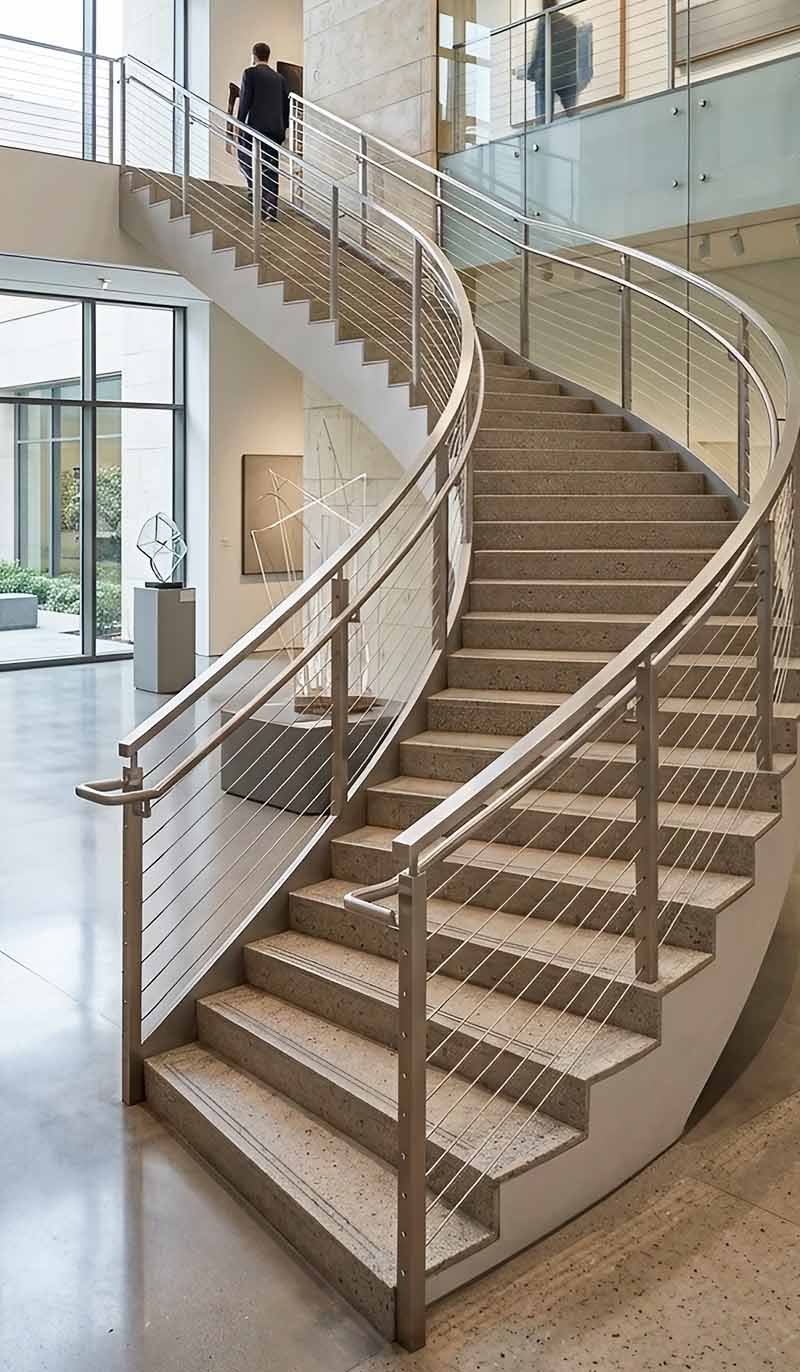 Modern stainless steel balustrades and railings along staircase with glass panels and architectural interior design.