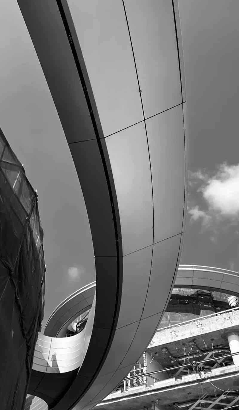 Flowing double-curved aluminium facade panels wrapping sections of a contemporary architectural exterior